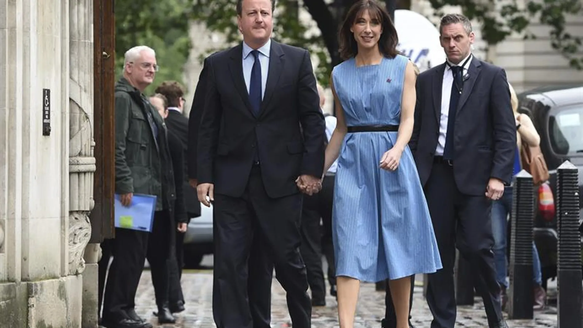 Cameron acudió a la votación vestido con traje y corbata oscuros, mientras que su esposa llevaba un vestido azul sin mangas ajustado con un cinturón negro