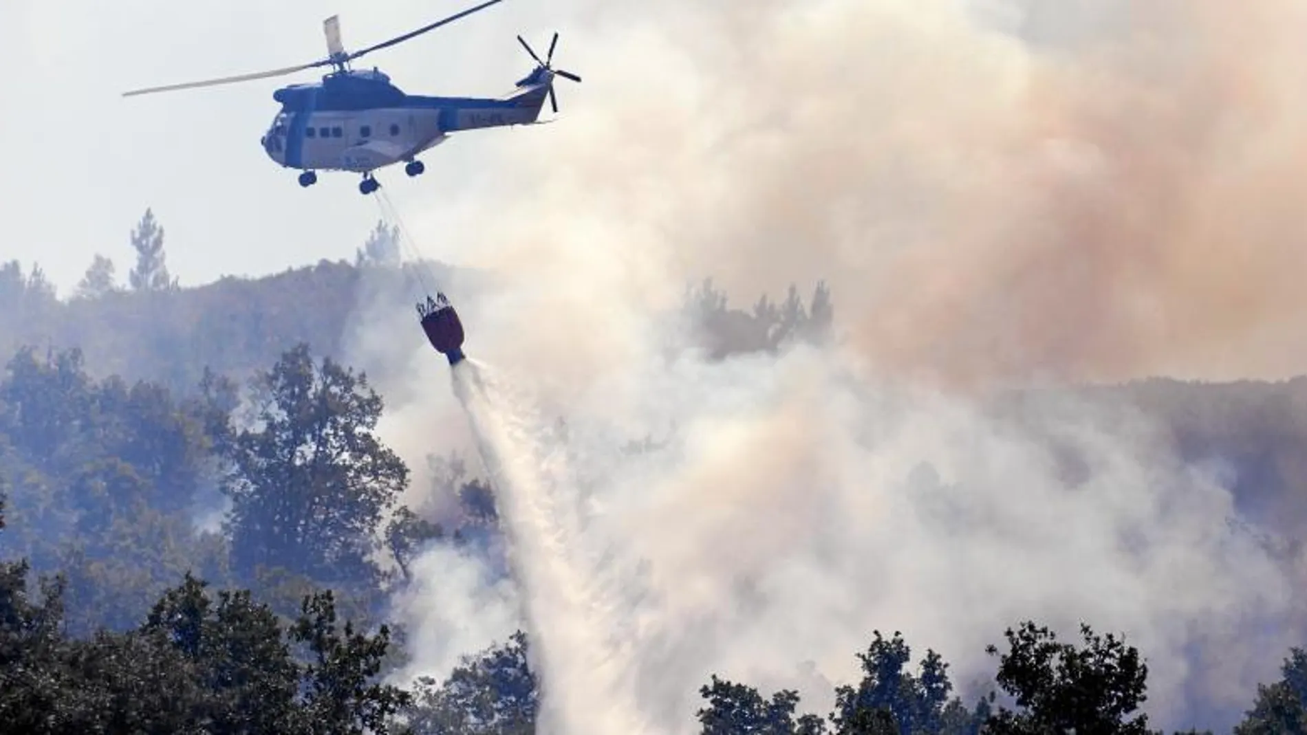 Un helicóptero realiza las labores de extinción del fuego que ayer permanecía activo en Pereiro de Aguiar (Orense)