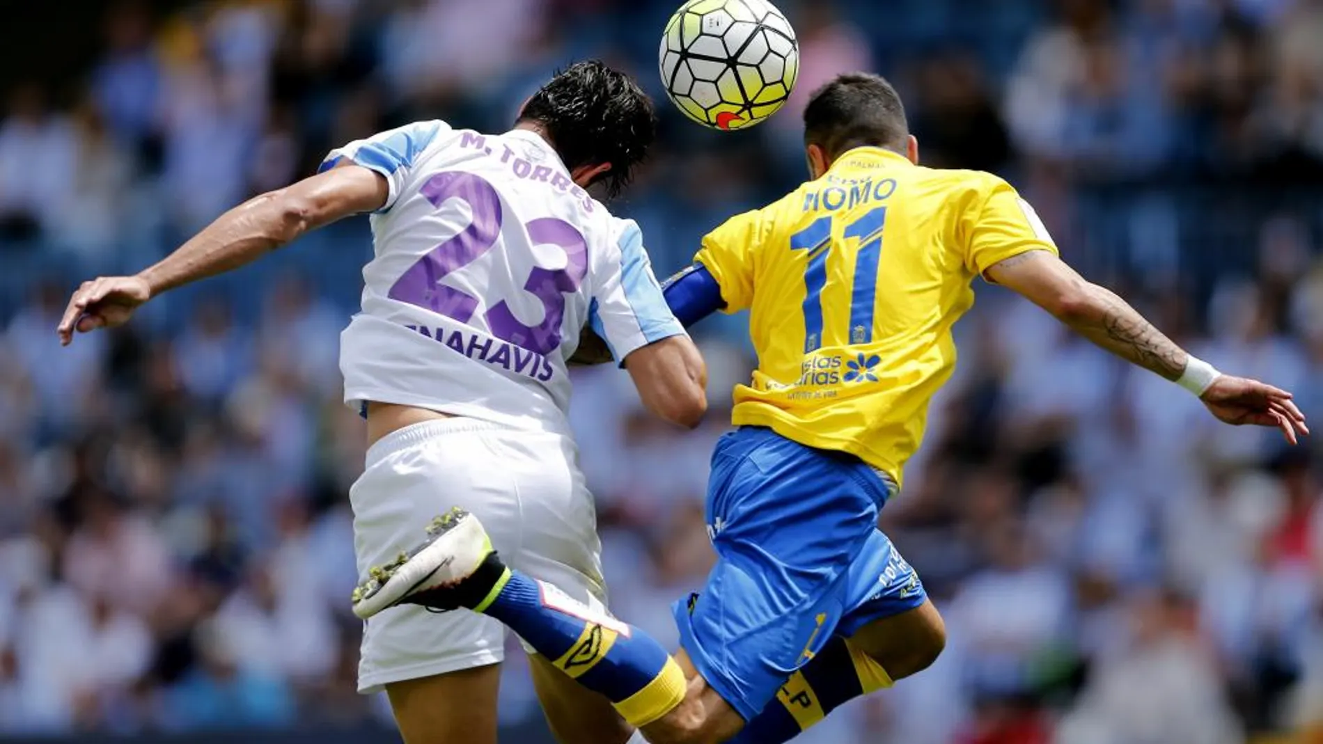 El defensa del Málaga Miguel Torres (i) y el centrocampista de la Unión Deportiva las Palmas Momo Figueroa (d), saltan por el balón durante el partido.