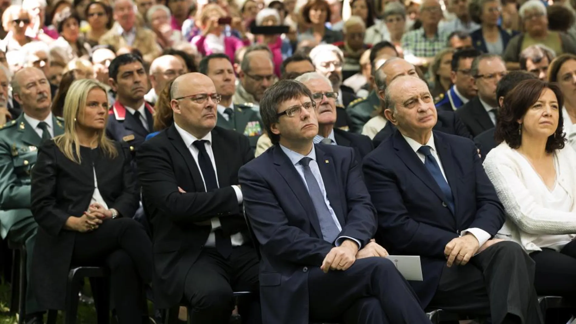 El ministro del Interior en funciones, Jorge Fernández Díaz, junto al presidente de la Generalitat de Cataluña, Carles Puigdemont, durante el acto de homenaje a las víctimas del terrorismo, al cumplirse 25 años del atentado de ETA en la casa cuartel de la Guardia Civil de Vic