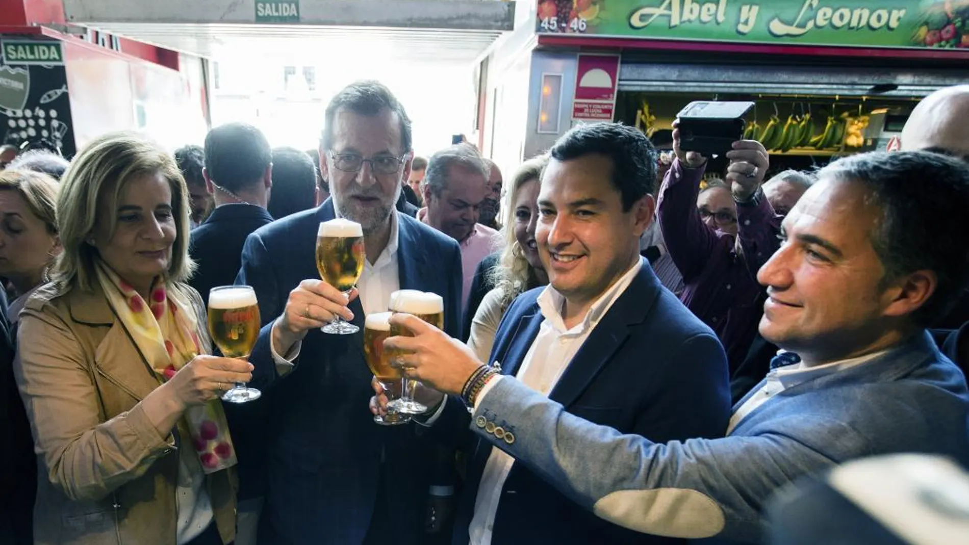 El presidente del Gobierno en funciones, Mariano Rajoy (c), el presidente del PP andaluz, Juanma Moreno (2d), la ministra de Empleo y Seguridad Social en funciones, Fátima Báñez (i) brindan con unas cañas de cerveza en el Mercado de Atarazana, durante el recorrido por el centro de Málaga.
