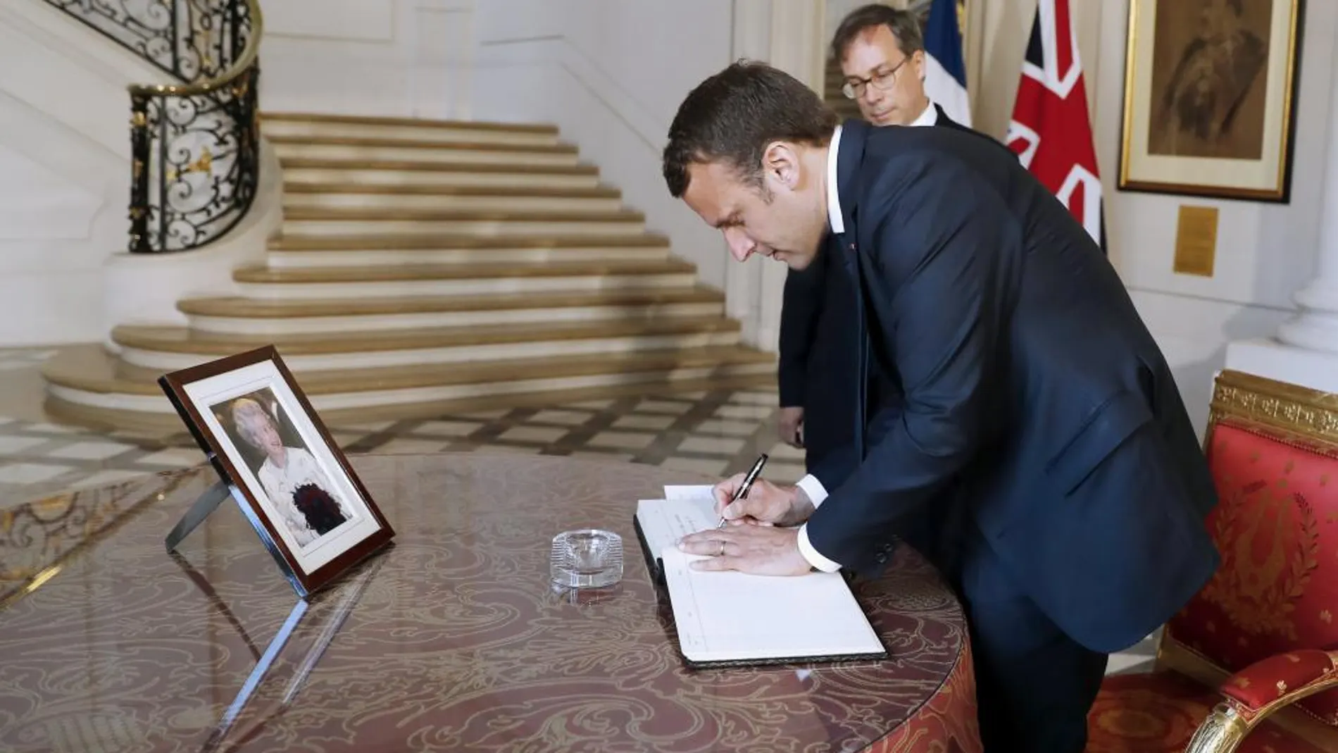 Emmanuel Macron firma un libro de condolencias en memoria de las víctimas del atentado de Manchester junto al embajador inglés en Francia, Edward Llewellyn.