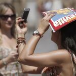 Una turista se fotografía mientras se proteje del sol con una guía turística de Sevilla
