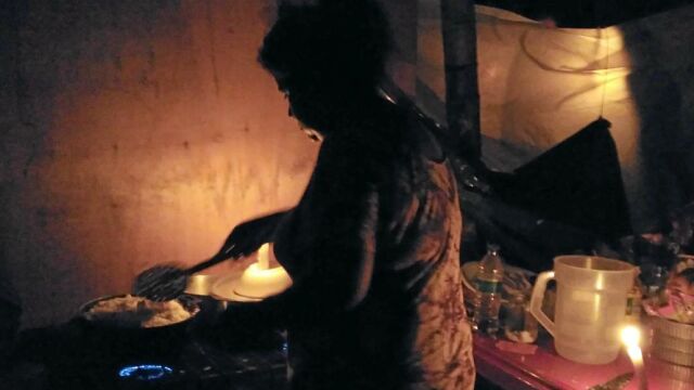 María Hurtado, mujer de Manuel, prepara comida para la familia con los pocos recursos que tiene a su alcance en el campamento
