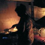 María Hurtado, mujer de Manuel, prepara comida para la familia con los pocos recursos que tiene a su alcance en el campamento