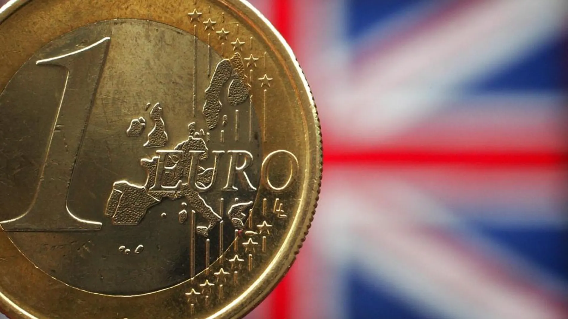 Una moneda de 1 euro ante una bandera de Reino Unido