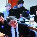 Imagen de la vista oral en la pantalla del circuito cerrado del juzgado en la que se ve a los padres de Asunta, junto con el abogado defensor de la primera, José Luis Gutiérrez Aranguren.