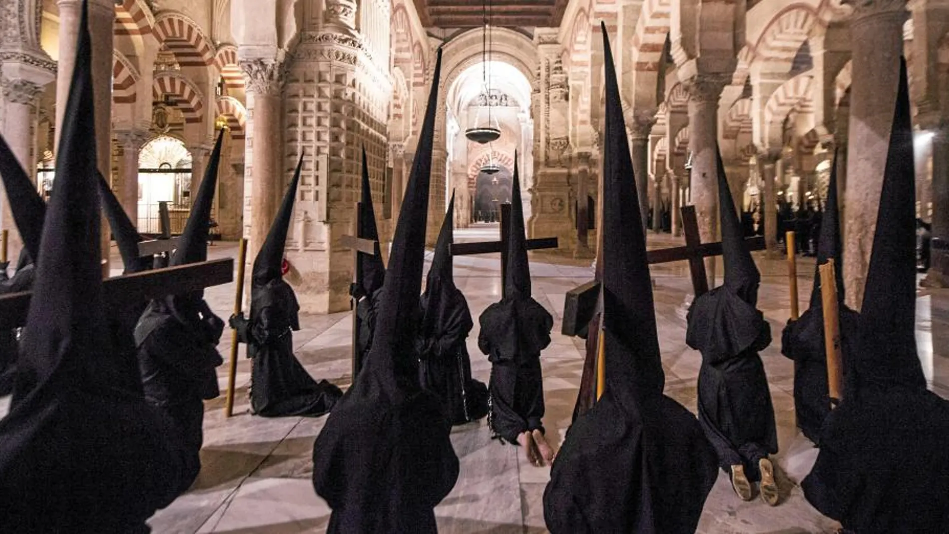 Nazarenos de una de las cofradías de Córdoba que procesionó ayer pasa por la catedral durante la realización de su estación de penitencia