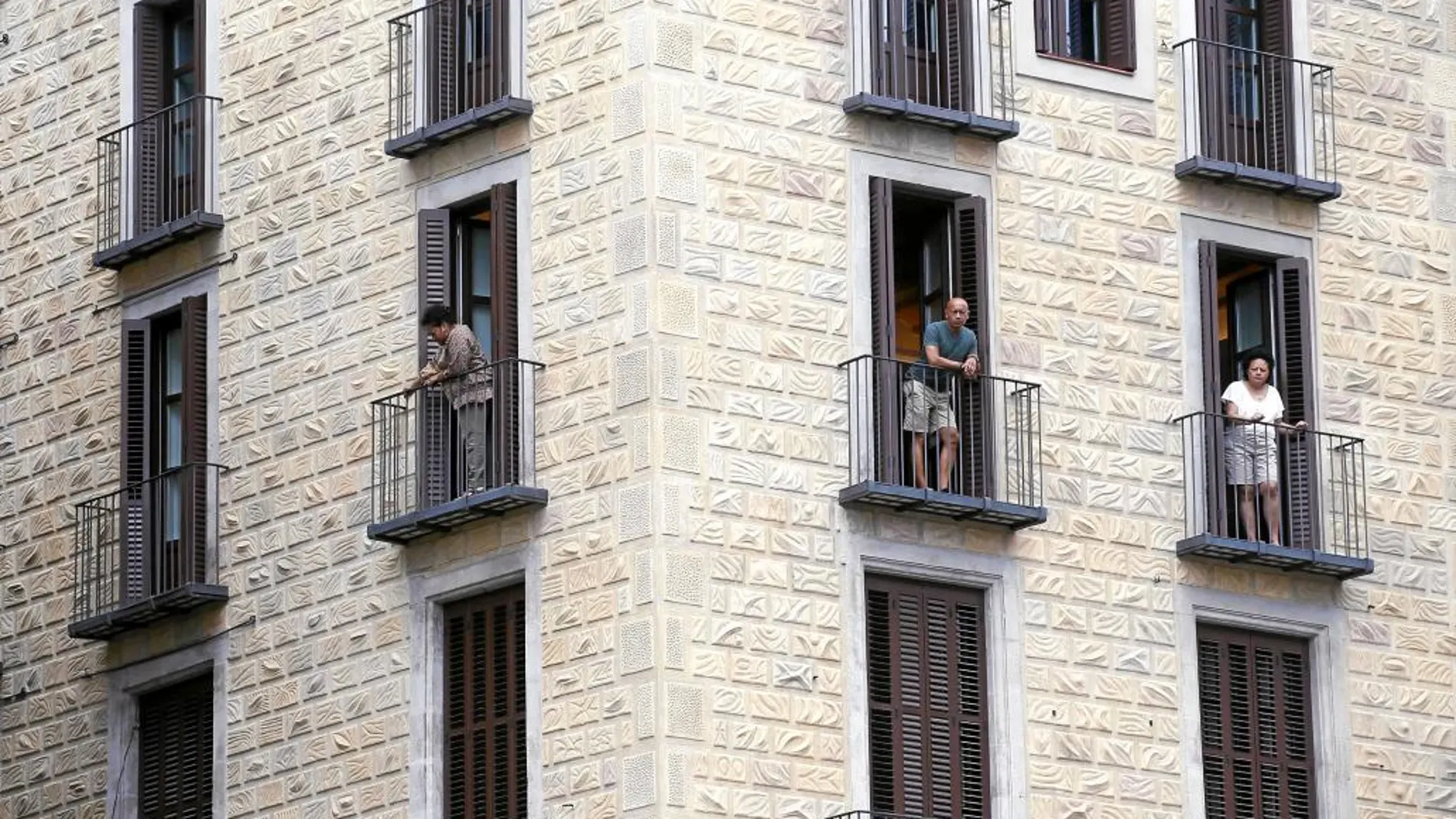 Unos turistas en los balcones de un edificio de apartamentos con vistas a la plaza Sant Jaume