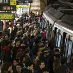 Usuarios del Metro de Barcelona esperan en el andén de la estación de Plaza España la llegada de un convoy durante los servicios mínimos decretados en la jornada de huelga de Metro