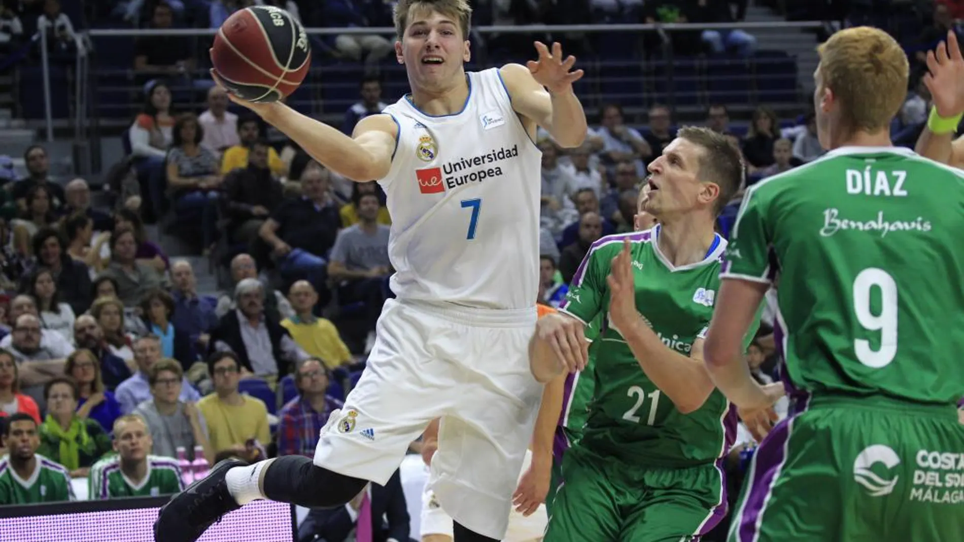 El base esloveno del Real Madrid Luka Doncic intenta avanzar con el balón ante el alero polaco del Unicaja Adam Waczynski