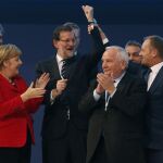 Donald Tusk (d), levanta el brazo de Rajoy (c), junto al presidente el PPE, Joseph Daul (2d), y Angela Merkel (i), mientras posan para la foto de familia del Congreso del Partido Popular Europeo (PPE).