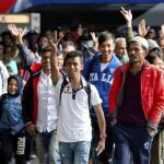 Varios refugiados saludan a su llegada a la estación de tren de Munich, donde han llegado hoy cerca de 5.000.