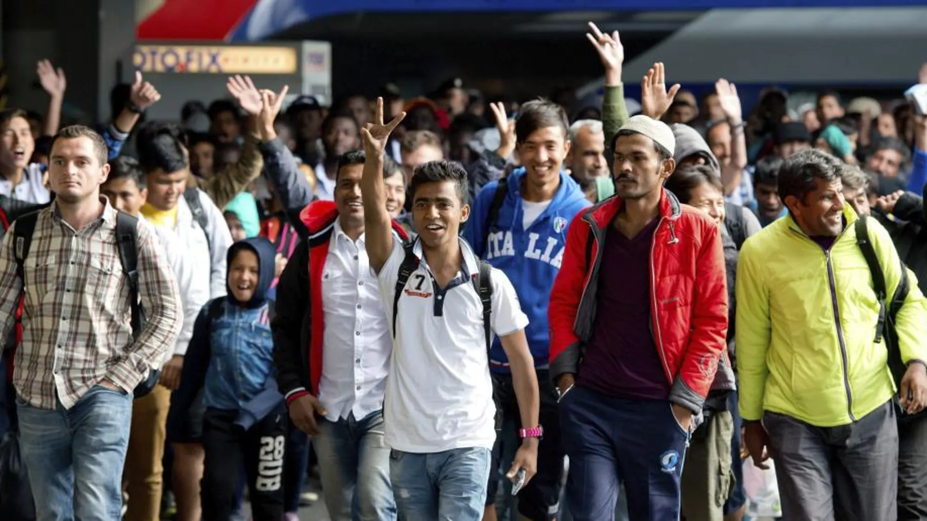 Varios refugiados saludan a su llegada a la estación de tren de Munich, donde han llegado hoy cerca de 5.000.