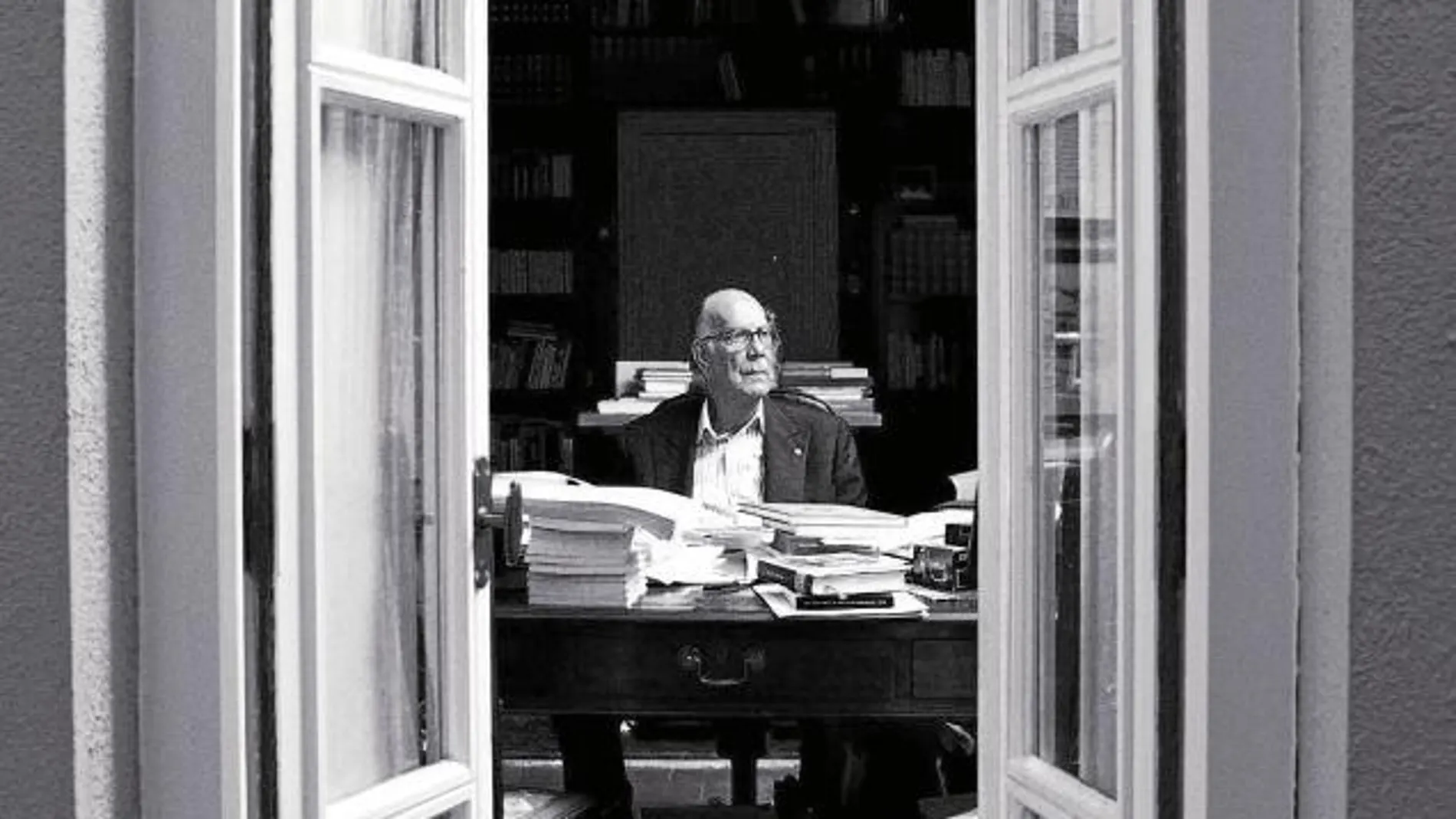 Camilo José Cela, entre libros y folios, posa en la mesa de trabajo de su estudio