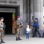 Una niña se deja fotografiar por un familiar junto a dos soldados que vigilan la entrada de una estación belga