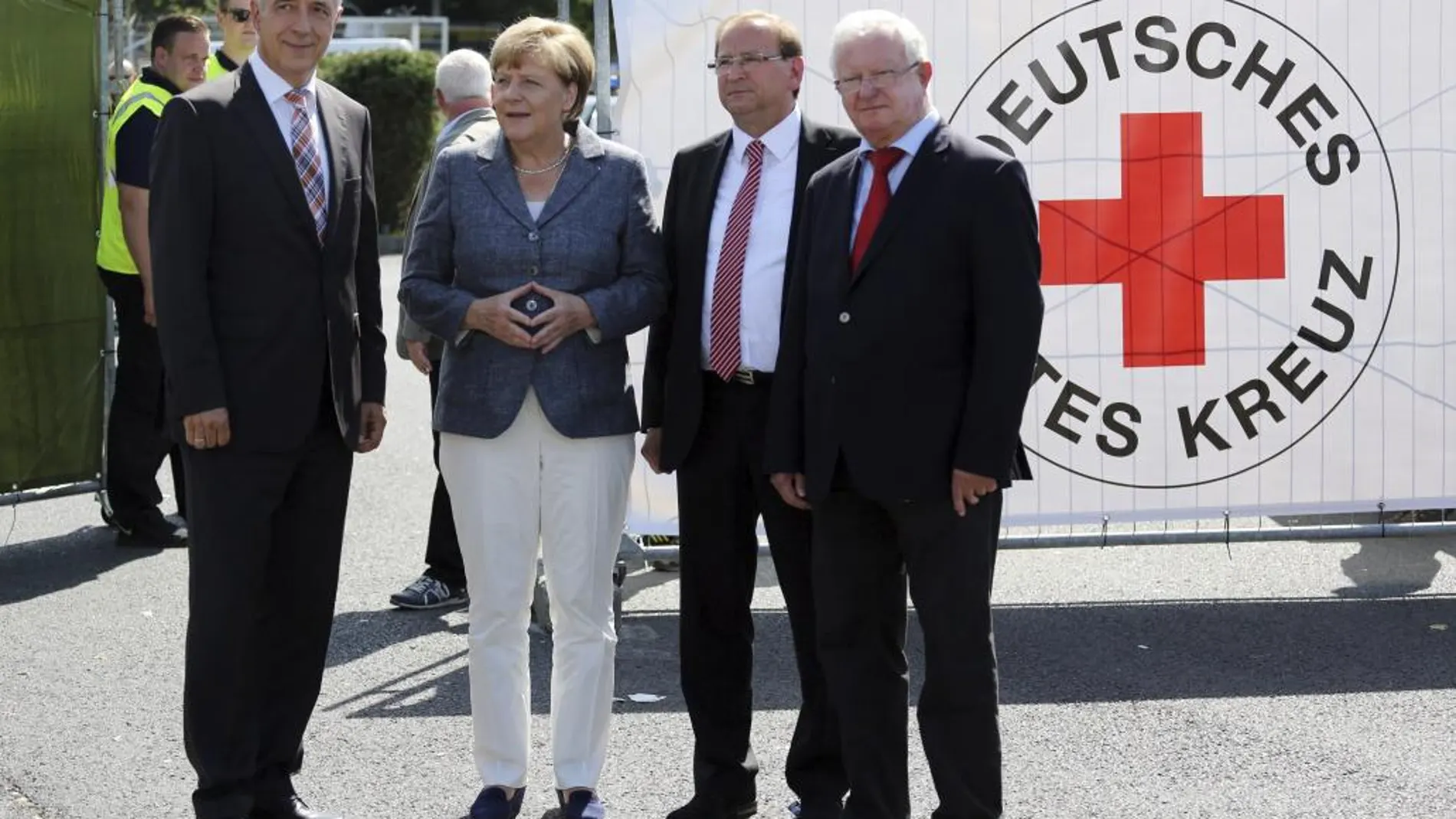 La canciller alemana, Angela Merkel (2i), el jefe del Gobierno del estado de Sajonia, el cristianodemócrata Stanislaw Tillich (i), el presidente de la Cruz Roja alemana, Rudolf Seiters, y el alcalde de Heidenau, Jürgen Optiz (2d), durante su visita al centro de refugiados objeto de violencia por parte de grupos neonazis