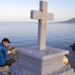 Un migrante pakistaní, sentado tras una cruz, ayer, en el puerto de Mytilene, en la isla de Lesbos