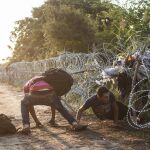 Varios inmigrantes pasan la alambrada en la frontera entre Hungría y Serbia