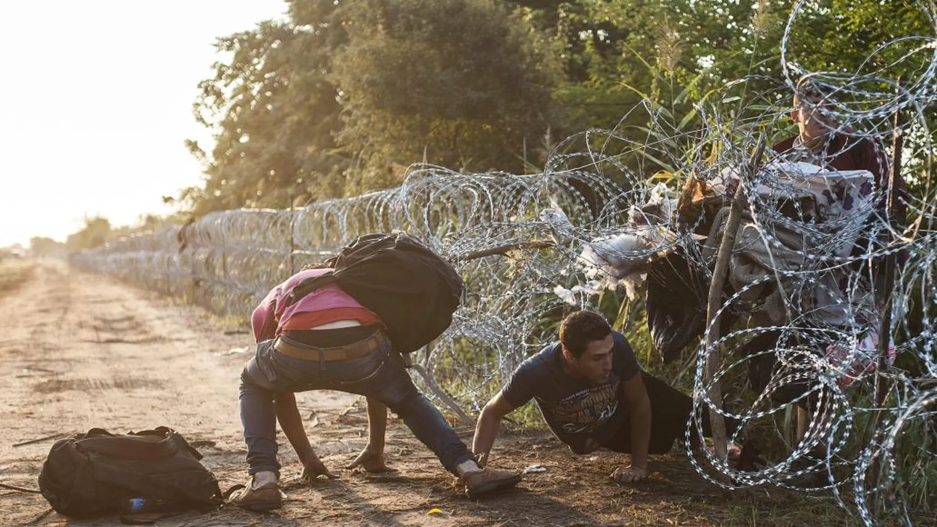 Varios inmigrantes pasan la alambrada en la frontera entre Hungría y Serbia