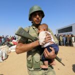 Un soldado turco sostiene en brazos a un bebé sirio en un campo de refugiados.