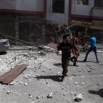 Varias personas hacen balance de los daños tras un bombardeo del ejército sirio en Douma