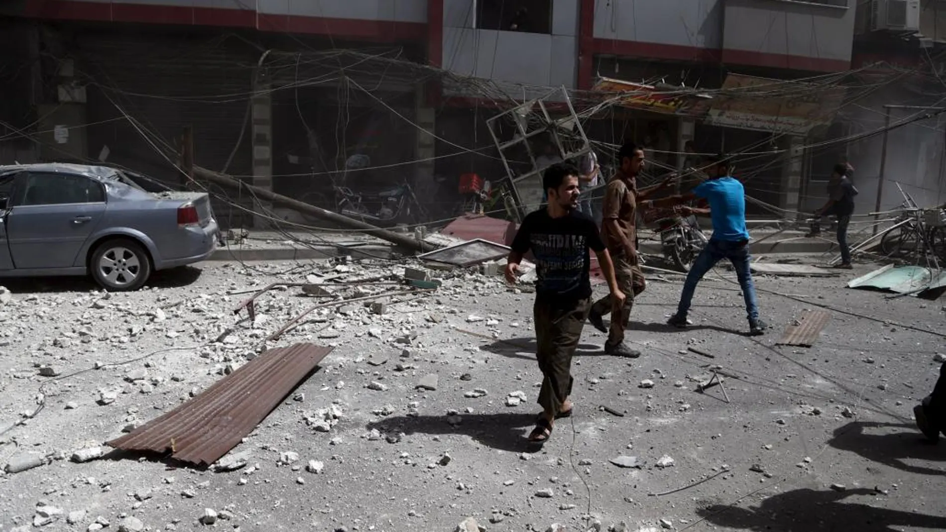 Varias personas hacen balance de los daños tras un bombardeo del ejército sirio en Douma