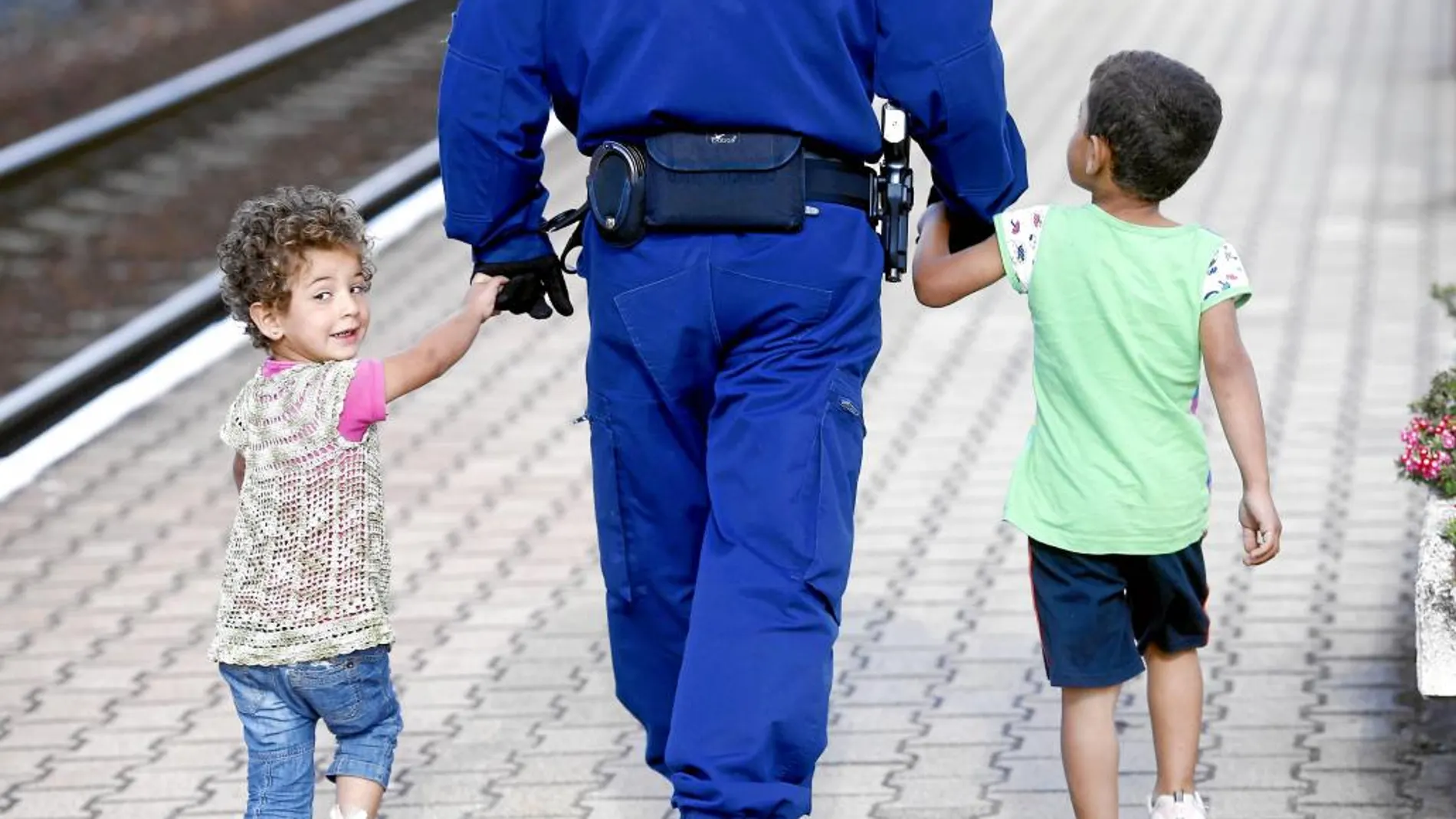 Un policía escolta a dos niños sirios en la estación de Hegyeshalom, en Múnich, ayer