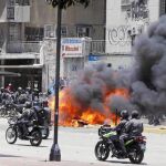 Miembros de las fuerzas del orden venezolanas pasan junto a un incendio provocado en una de las calles de Caracas ayer