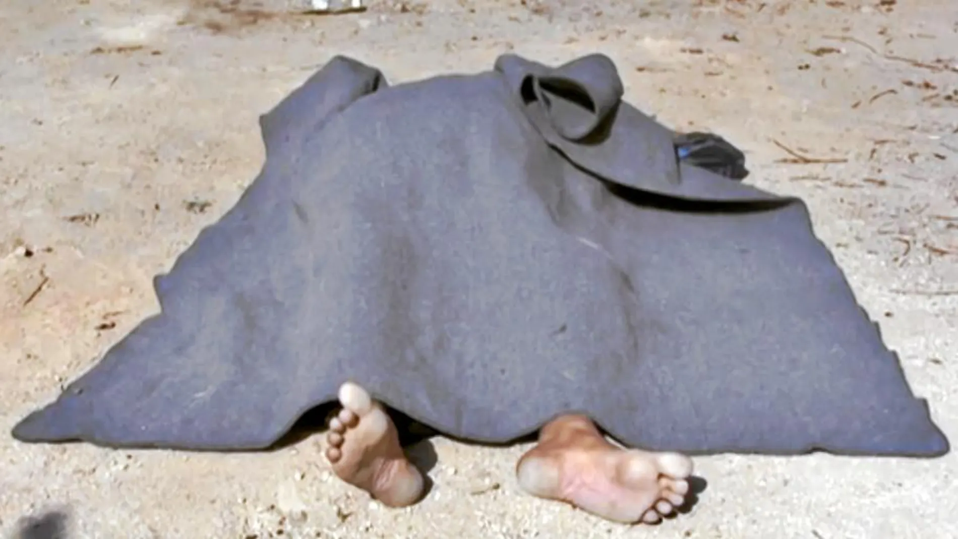 Uno de los cadáveres de los civiles hallados en la ciudad siria de Al Qariatain es cubierto con una manta