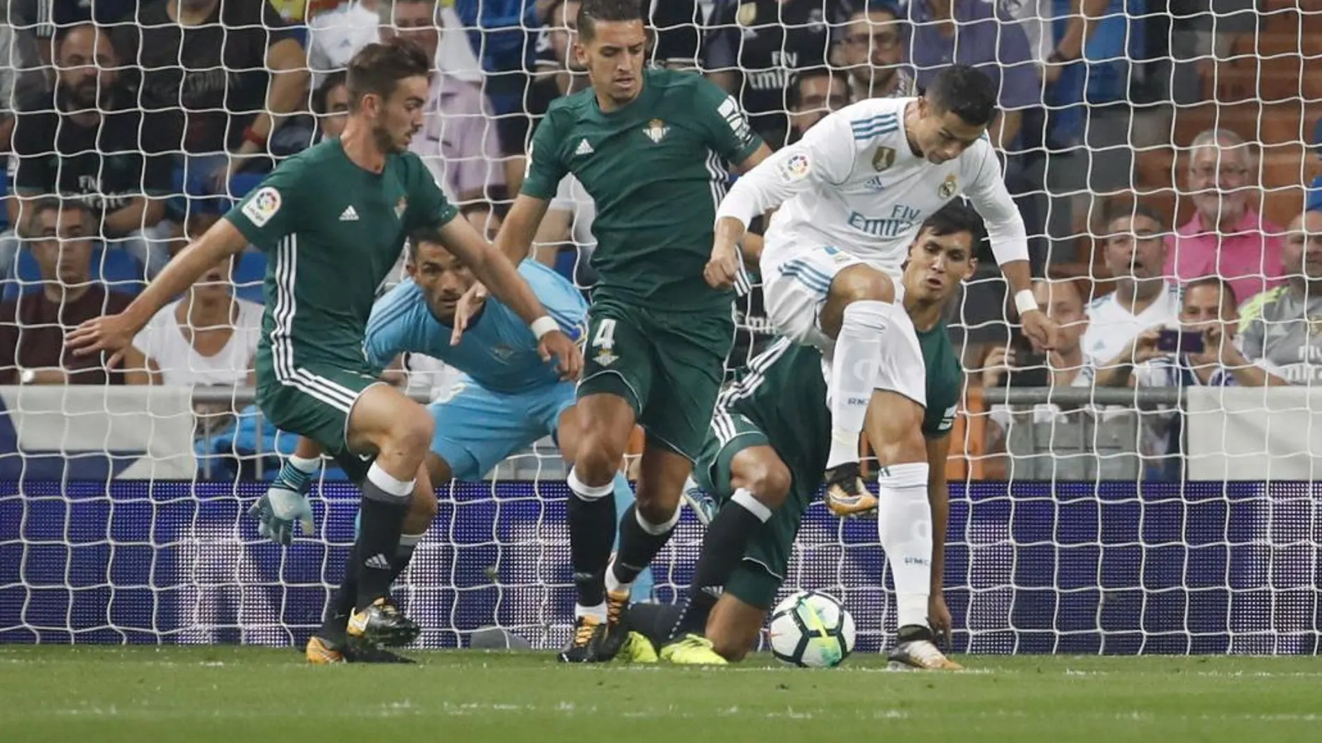 El delantero portugués del Real Madrid, Cristiano Ronaldo (d), intenta rematar de tacón ante los defensores del Real Betis