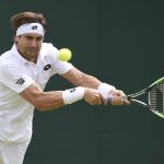 El tenista español David Ferrer golpea la bola contra el francés Nicolas Mahut durante su partido de la segunda ronda del torneo de Wimbledon