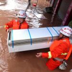 Los bomberos rescatan los muebles de una de las viviendas inundadas