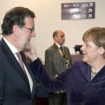 La canciller alemana Angela Merkel toca a Mariano Rajoy en la cara, donde recibió el puñetazo.