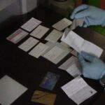UN agente analiza las tarjetas y documentos intervenidos durante uno de los registros domiciliarios