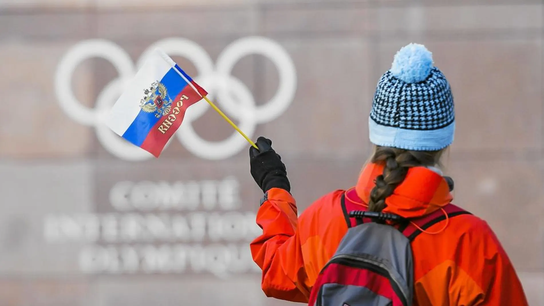 Una mujer porta una bandera rusa enfrente del edificio en el que se celebró el Comité Ejecutivo del Comité Olímpico Internacional
