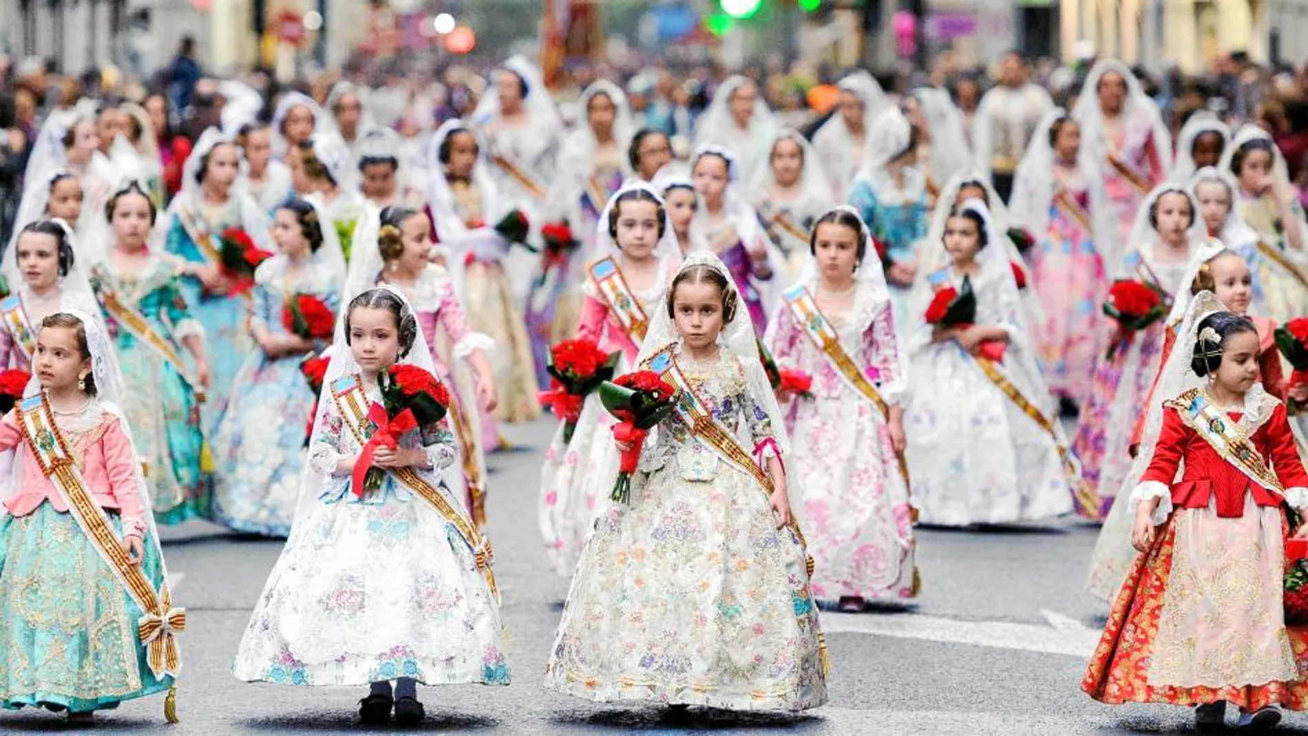 Las falleras más pequeñas inundan con sus mantillas blancas y claveles rojos las calles de toda la ciudad