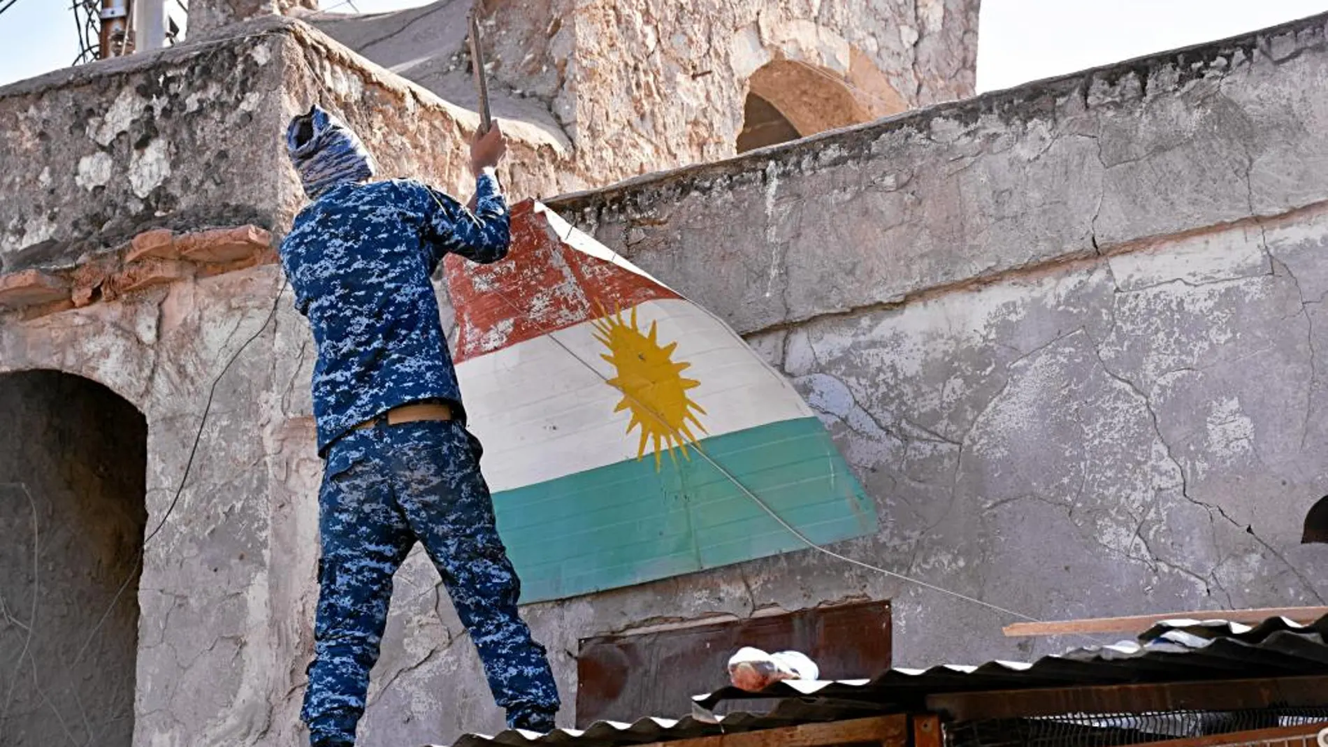 Un soldado iraquí quita una bandera kurda de una vivienda en Altun Kupri, a las afueras de Erbil