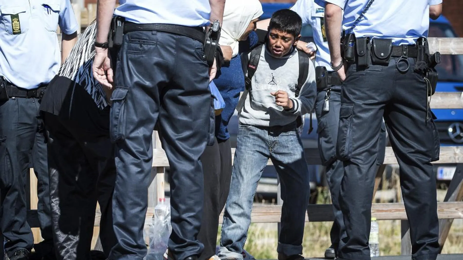 Un niño intenta evitar que su madre baje del tren para subir a un autobús en la estación de Rodby (Dinamarca)