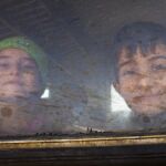 Dos niños sonríen desde el interior de un tren con dirección a la frontera serbia, en la ciudad de Gevgelija (Macedonia)
