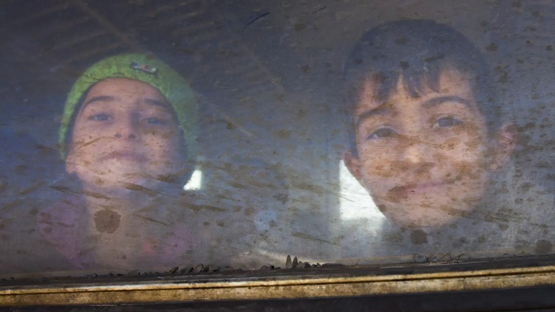 Dos niños sonríen desde el interior de un tren con dirección a la frontera serbia, en la ciudad de Gevgelija (Macedonia)