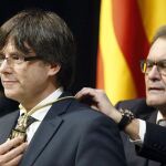 Artur Mas impone la medalla representativa del cargo al nuevo presidente de la Generalitat de Cataluña, el independentista Carles Puigdemont.