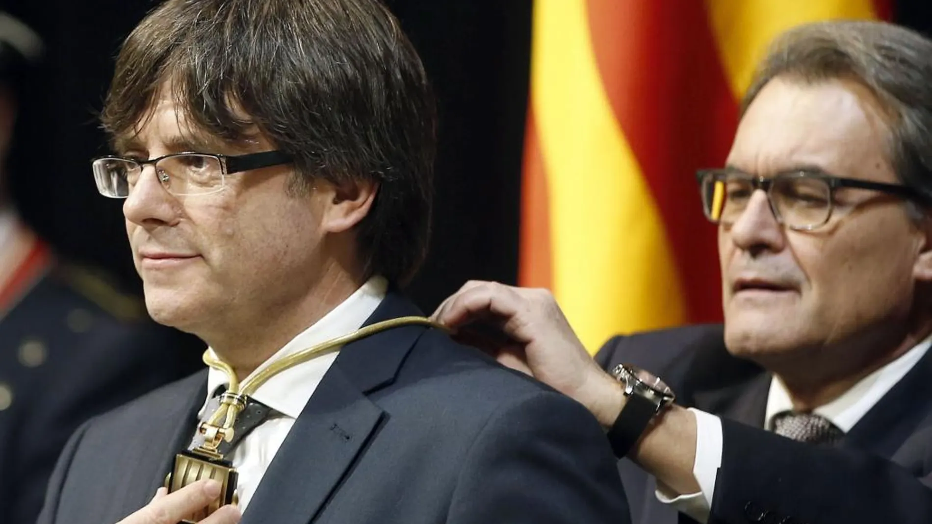 Artur Mas impone la medalla representativa del cargo al nuevo presidente de la Generalitat de Cataluña, el independentista Carles Puigdemont.
