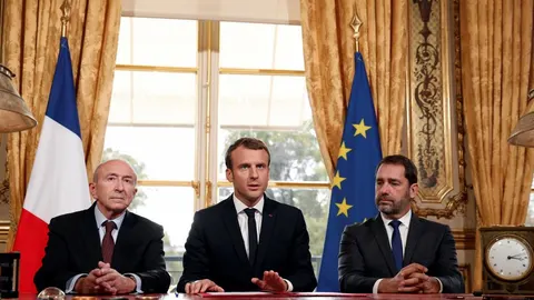 El presidente francés Emmanuel Macron atiende a los medios junto al ministro de Interior Gerard Collomb (izda), y al portavoz del Gobierno, Christophe Castaner, tras la firma de una nueva ley antiterrorista en el Palacio del Elíseo