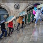 Varios turistas bajo la lluvia en la plaza de Platerías esta mañana en Santiago de Compostela