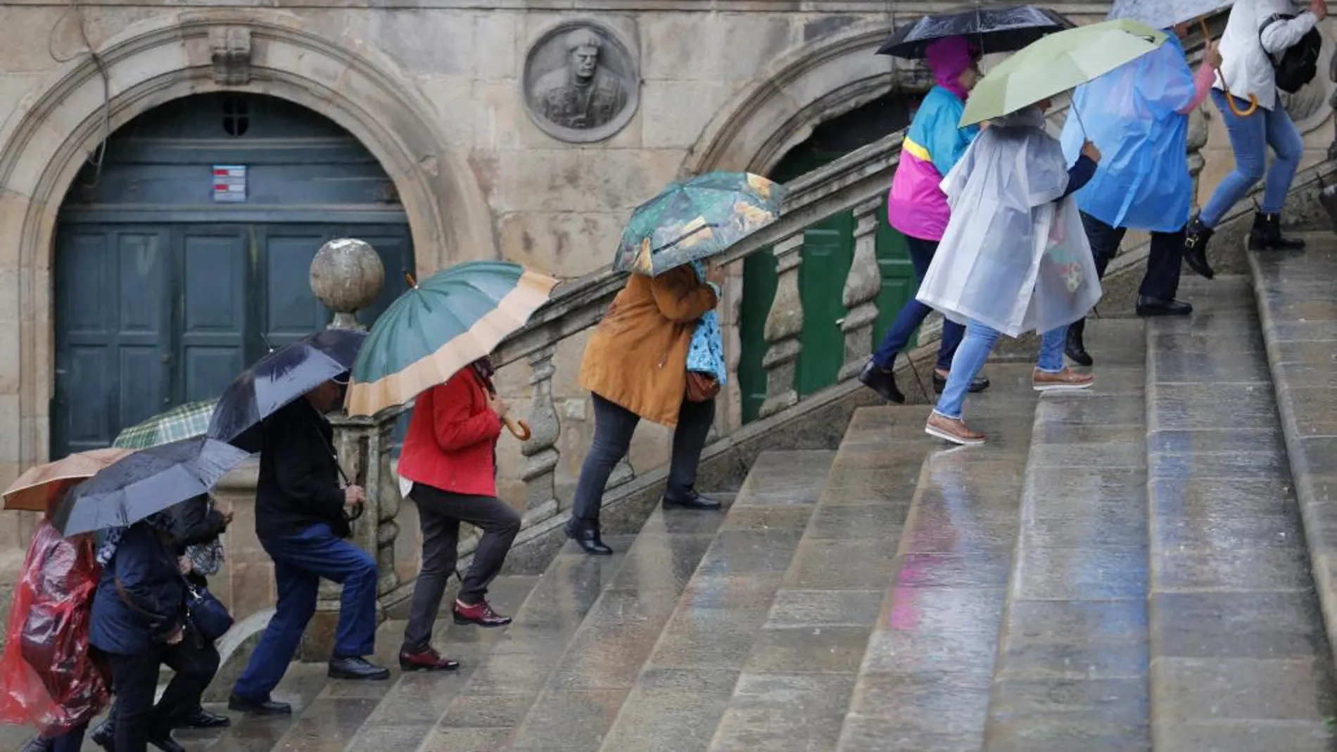 Varios turistas bajo la lluvia en la plaza de Platerías esta mañana en Santiago de Compostela