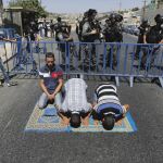 Palestinos rezan a las afueras de la ciudadela antigua de Jerusalé junto a oficiales de la Policía fronteriza israelí