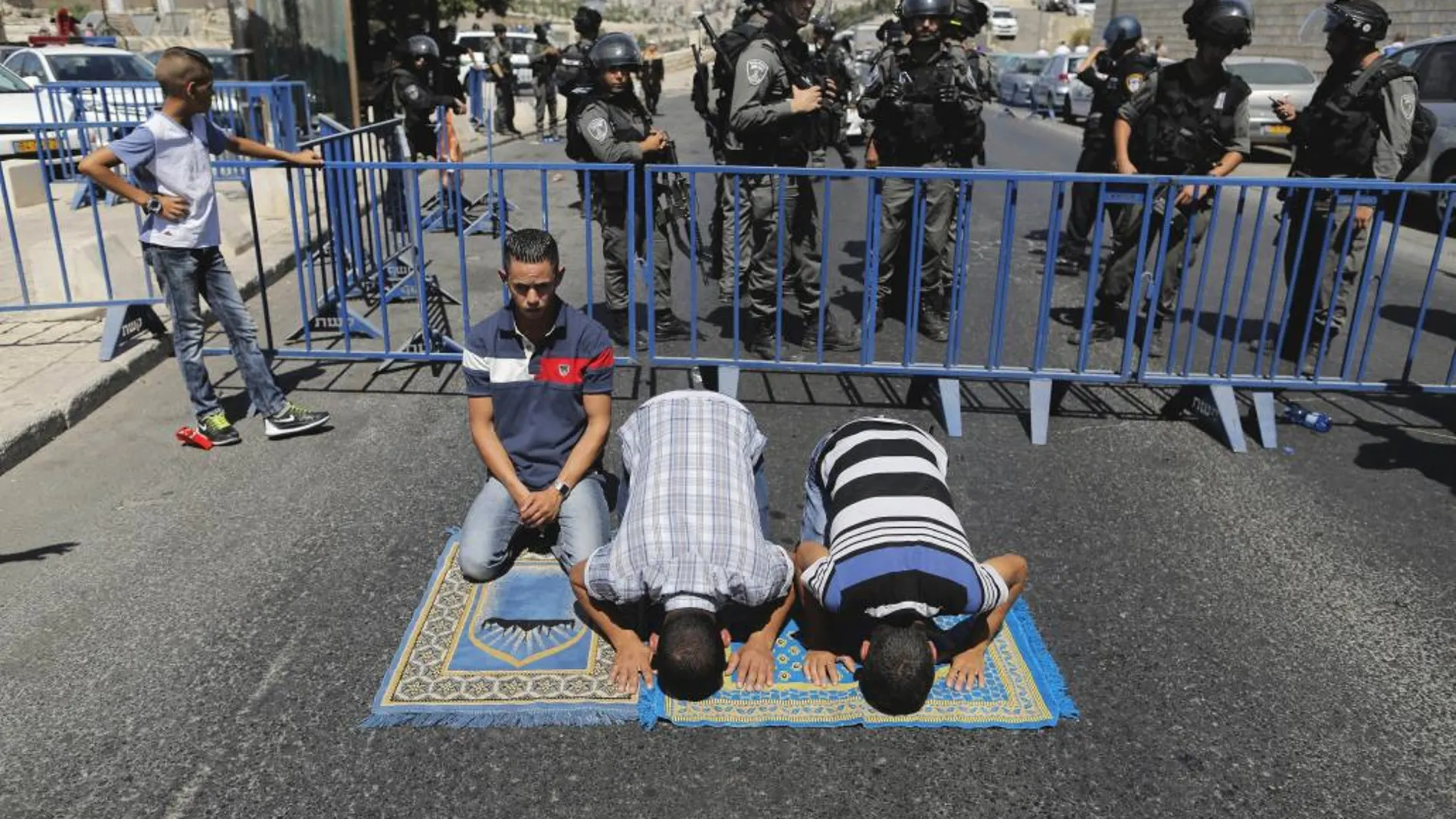 Palestinos rezan a las afueras de la ciudadela antigua de Jerusalé junto a oficiales de la Policía fronteriza israelí