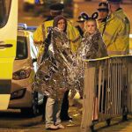 Dos jóvenes esperan junto a un coche policial en las inmediaciones del Manchester Arena tras el atentado