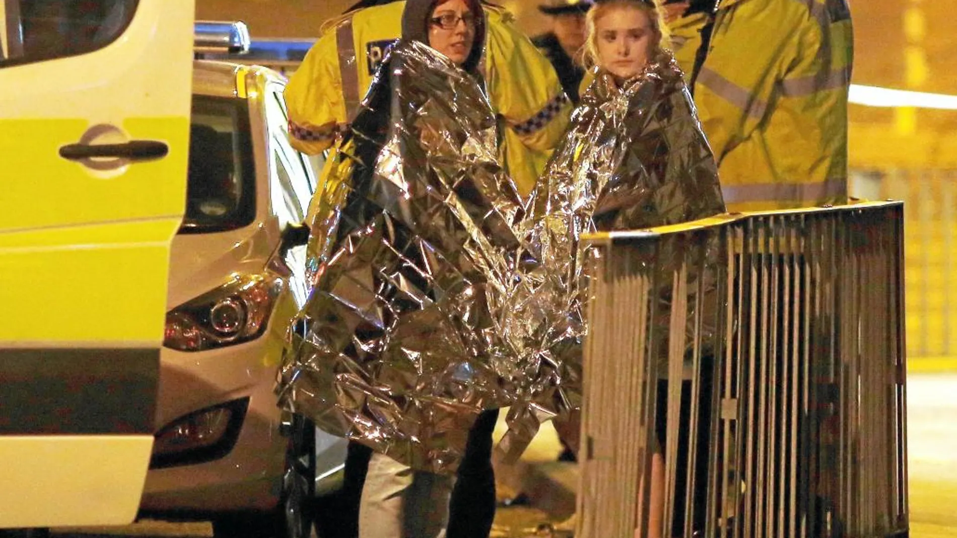 Dos jóvenes esperan junto a un coche policial en las inmediaciones del Manchester Arena tras el atentado